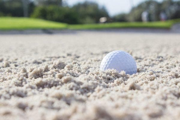 Balle de golf dans le sable d'un bunker